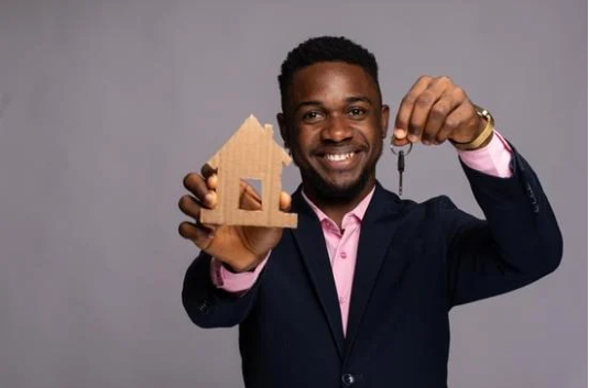 man holding model of house and keys